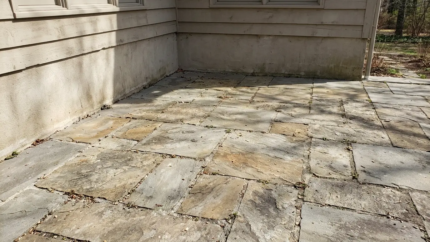 Before: a stone patio with a bare corner of a stone patio beside the house